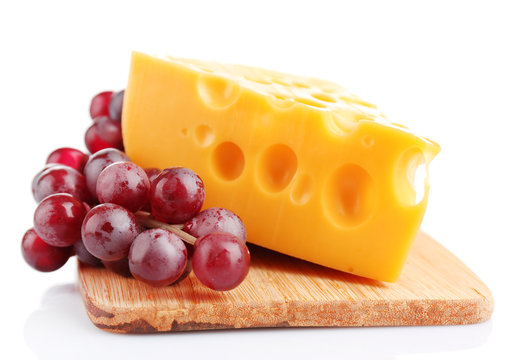 Piece of cheese and grape on wooden board, isolated on white