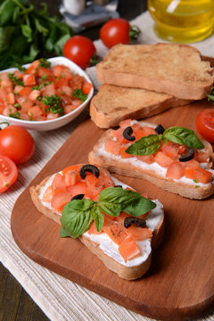 Delicious bruschetta with tomatoes on cutting board close-up