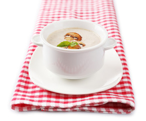 Mushroom soup in white pot, on napkin, isolated on white