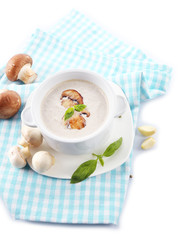 Mushroom soup in white pot, on napkin, isolated on white