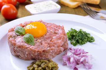 Delicious steak tartare with yolk on plate on table close-up