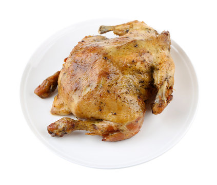 Whole roasted chicken on plate, isolated on white