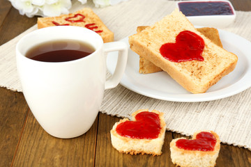 Delicious toast with jam and cup of tea on table close-up