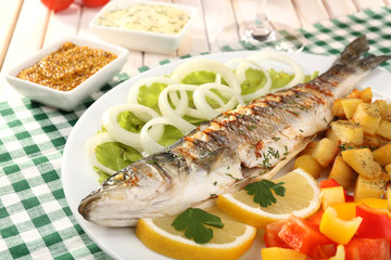 Delicious grilled fish on plate on table close-up