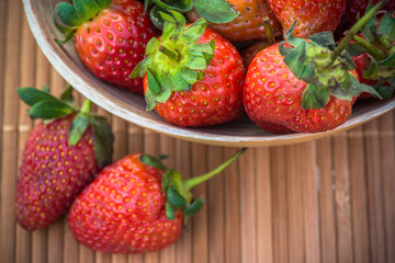 bowl filled with red strawberries on wooden textured table top