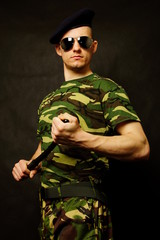 Young military man with nightstick at hand
