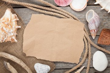 Old paper with rope and seashells on wooden textured background