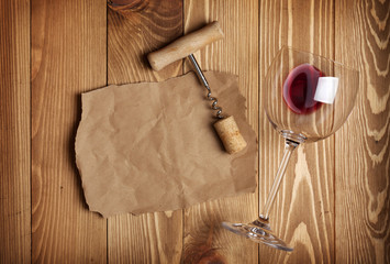 Red wine glass, corkscrew and paper for your note