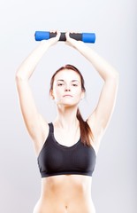 Young fit woman in sport bra during exercise with dumbbells