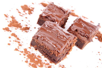 Slices of a brownie on white background covered with chocolate