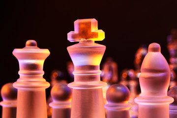 Glass chess on a chess board lit by blue and orange light