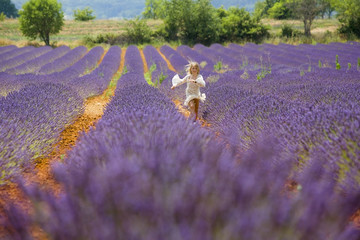 Young girl runs and jumps in a purple field of lavender