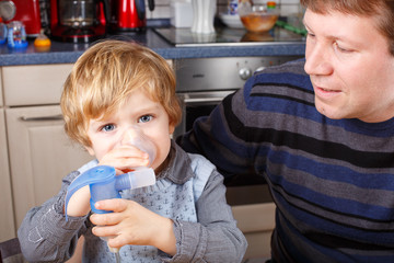 Little boy and his father making inhalation with nebuliser