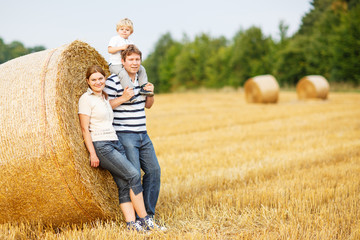happy family of three on yellow hay field in summer.