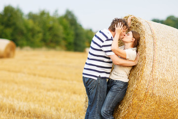 Naklejka na ściany i meble Young couple in love on yellow hay field on summer evening.