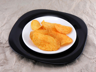 tasty potato chips in white plate on old paper