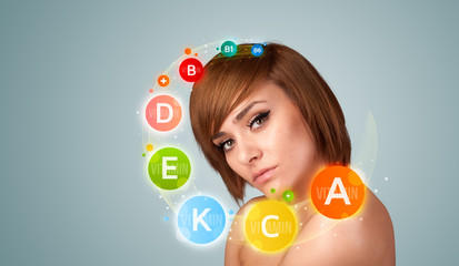 Pretty young girl with colorful vitamin icons and symbols