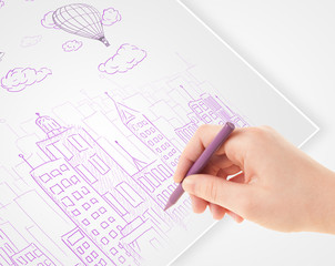 A person drawing sketch of a city with balloons and clouds on a