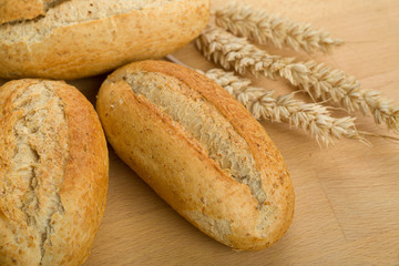 roll on wooden table with ears of wheat grain