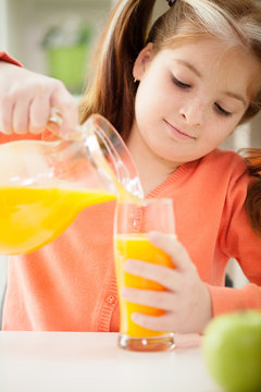 red-haired young girl drinking juice at home