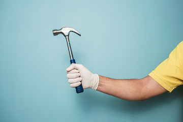 Man's gloved hand holding hammer