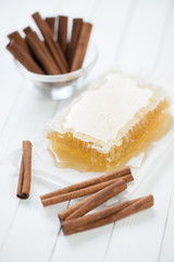 Fresh honey and cinnamon sticks, white wooden background
