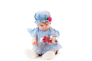 beautiful baby girl in a blue dress playing with a doll