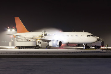 White plane with red tail during de-icing in winter