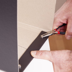 Man pulling with pliers screw on the box of fixed