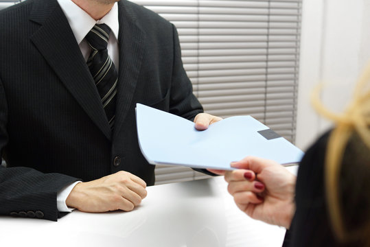 Employment interview with female applicant handing over a file c