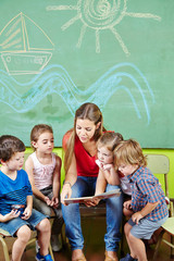 Erzieher und Kinder lesen Buch im Kindergarten
