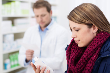 kundin in der apotheke schaut auf medikament