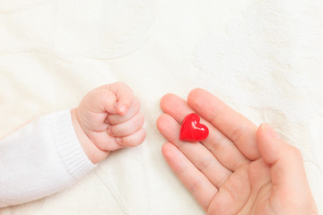 hands of mother and baby holding heart