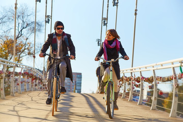 Young couple riding a bicycle across the bridge