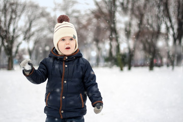 Fototapeta na wymiar Little boy playing with snow in winter park