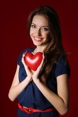 Attractive woman with heart, on red background