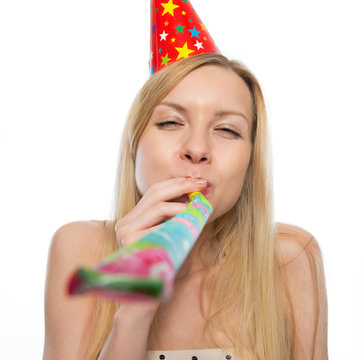Young woman blowing into party horn blower