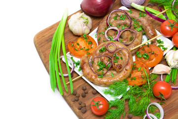 grilled sausages and vegetables on a cutting board on a white ba