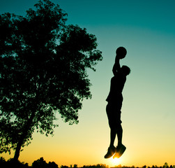 Player and basketball silhouette sunset background