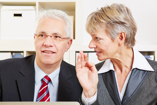 Business Woman Whispering Secret In Man's Ear