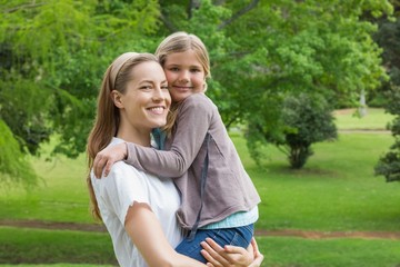 Fototapeta premium Mother carrying daughter at park
