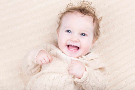 Funny laughing baby in a knitted dress
