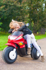 Beautiful little girl having fun on her toy motorcycle