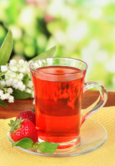 Delicious strawberry tea on table on bright background