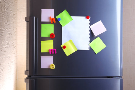 Empty paper sheets and colorful magnets on fridge door