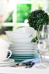 Clean dishes on table on window background