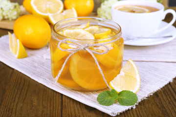 Tasty lemon jam with cup of tea on table close-up