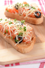 Delicious bruschetta with tomatoes on cutting board close-up