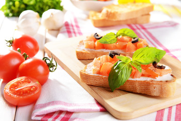 Delicious bruschetta with tomatoes on cutting board close-up