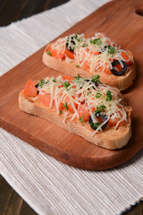 Delicious bruschetta with tomatoes on cutting board close-up